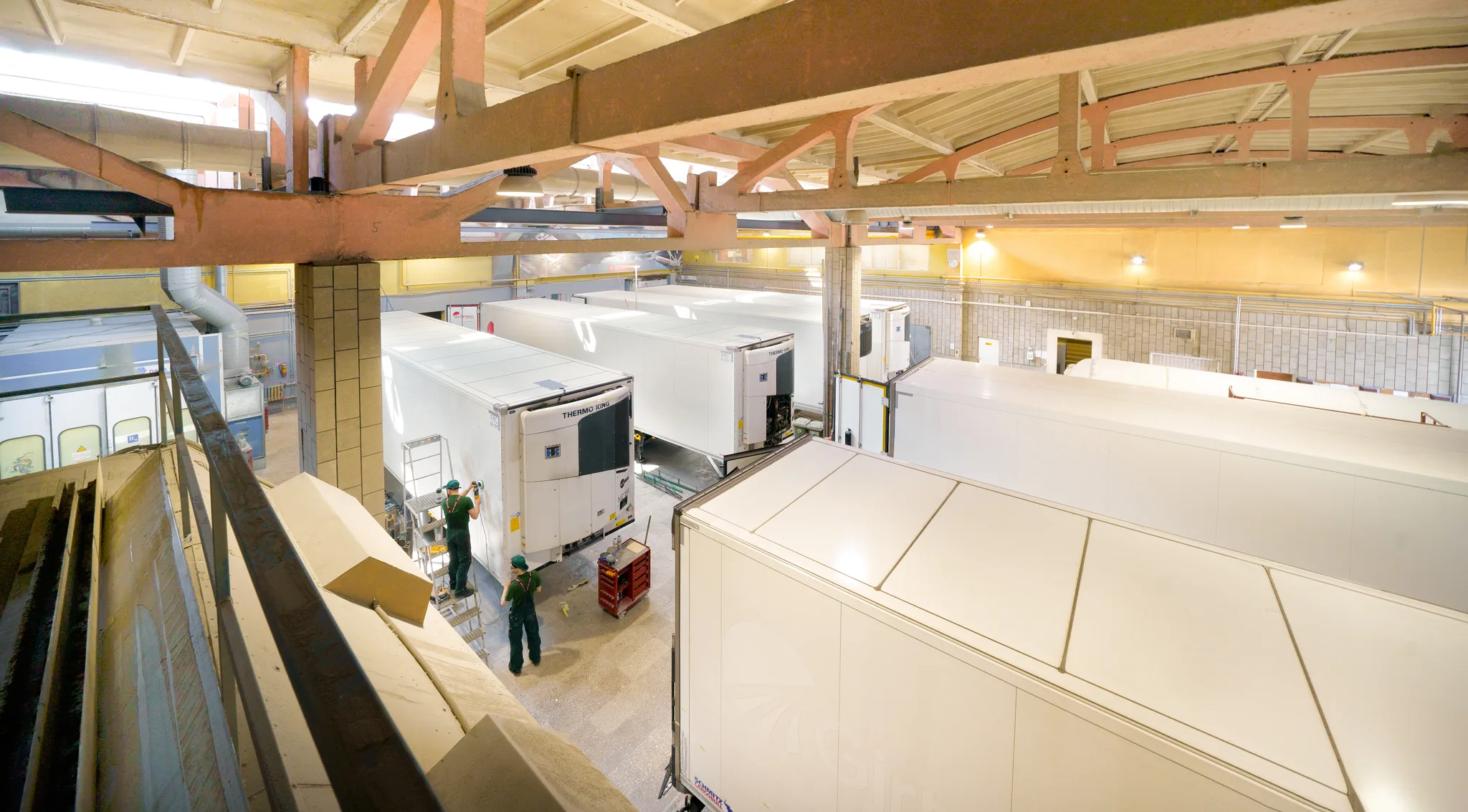Looking down the build hall over a row of bodies under construction, fitters working between them
